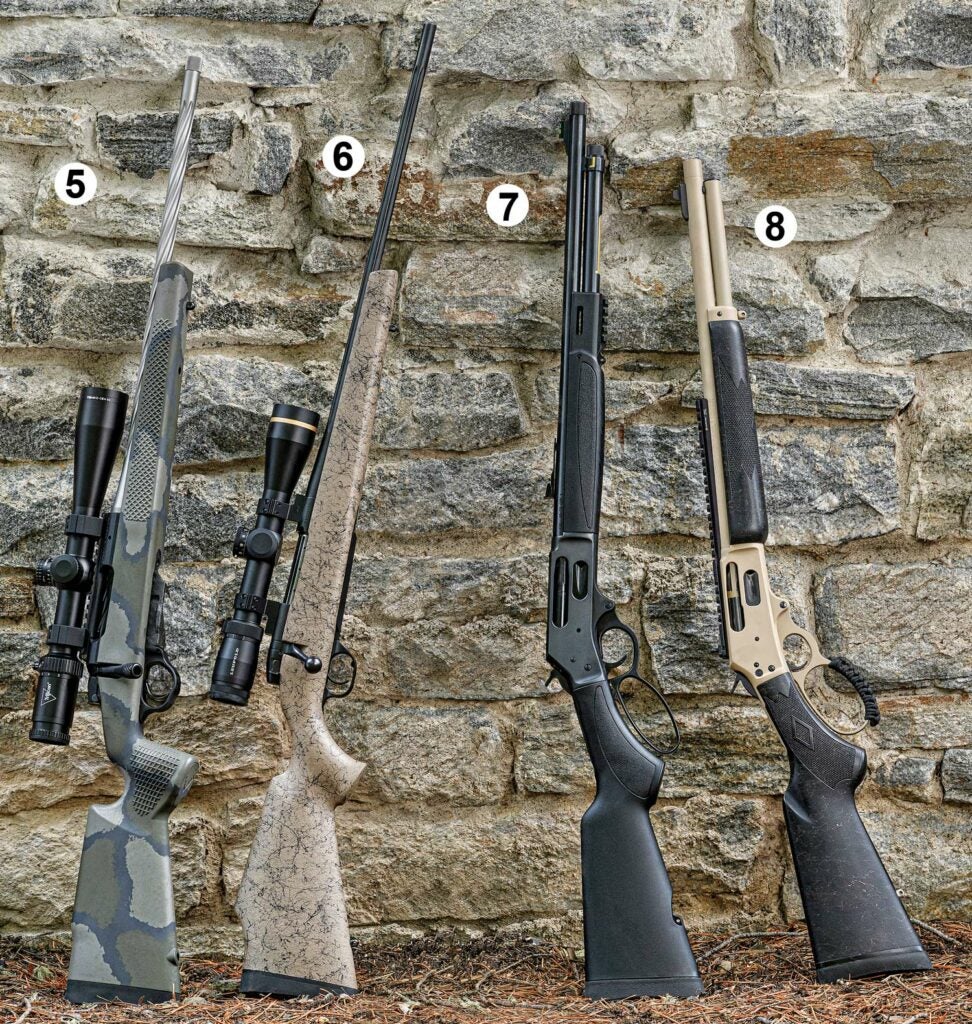 Four rifles leaning against a stone wall.