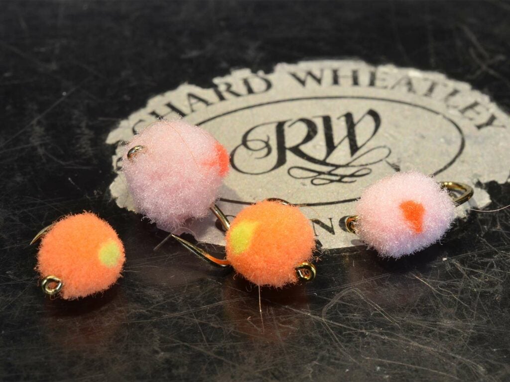 Four fuzzy fly lures mimicking the shape and color of salmon egg patterns.