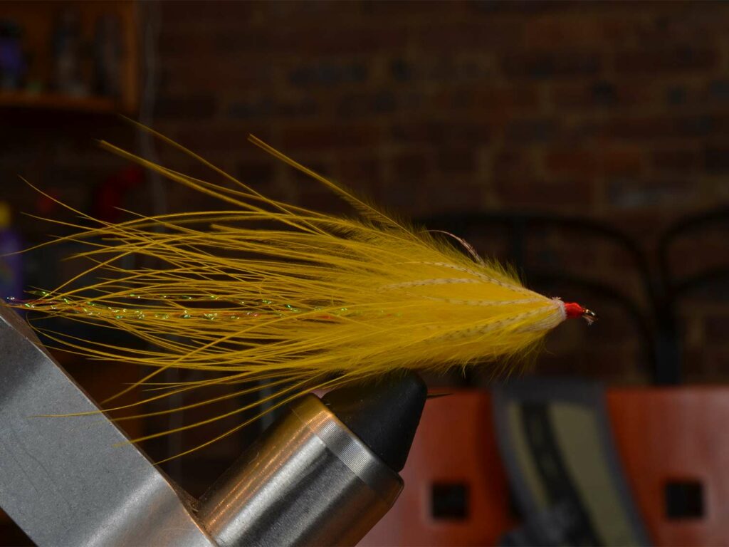 A yellow and fuzzy soft-hackle streamer fly lure.