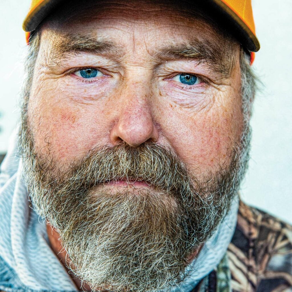 Close up portrait of a male hunter with a beard and cap.