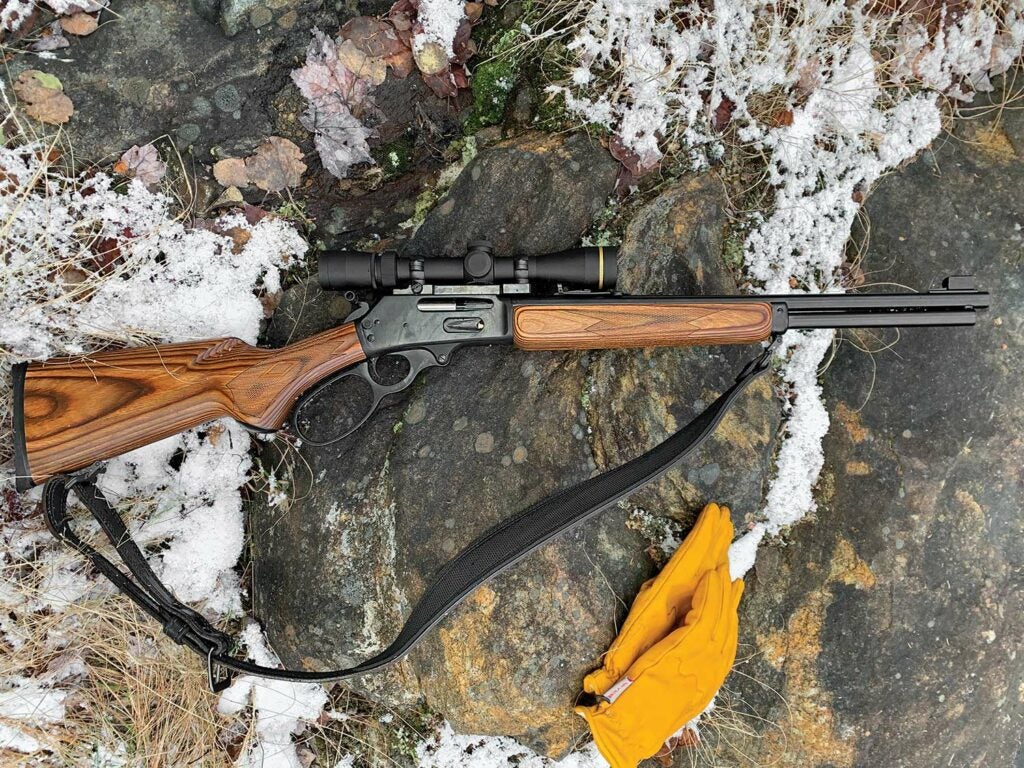 A lever-action rifle resting on a snow-covered rock.