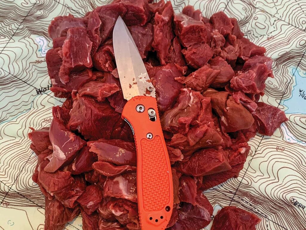 A knife resting on cubed meat and a laminated map.