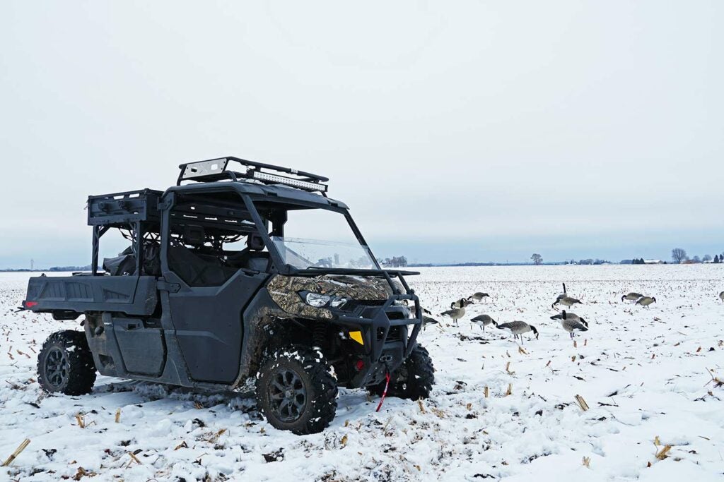 A Can-Am Defender Pro UTV in a field of snow next to goose decoys.
