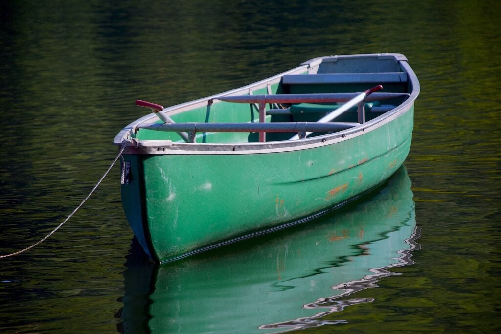 a single canoe tethered to a dock floats on the water.