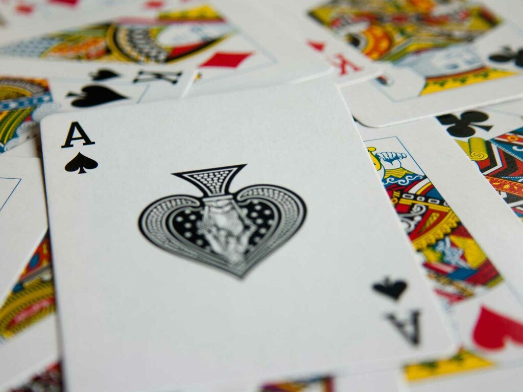 An Ace of Spades card on a pile of other playing cards.