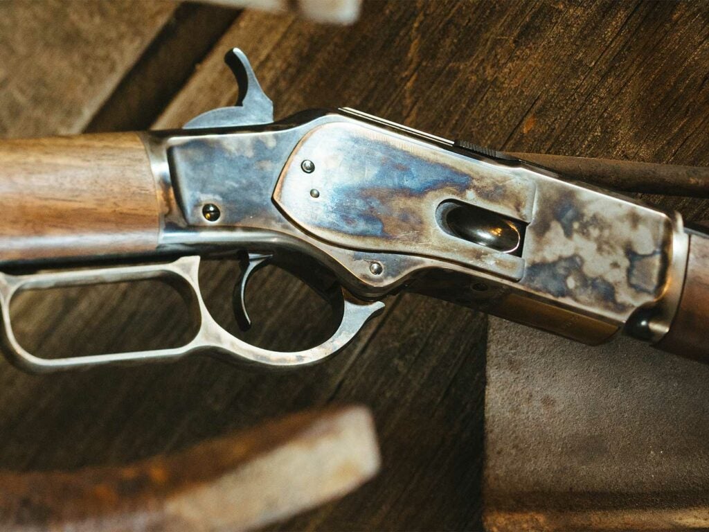 A close up detail of the metalwork on a lever-action rifle.