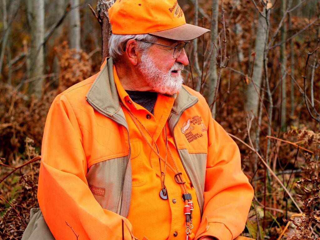 A hunter wears hunter orange in the woods.