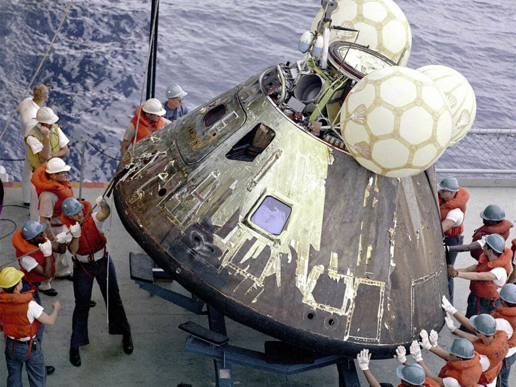 A group of people standing around the Apollo 13.