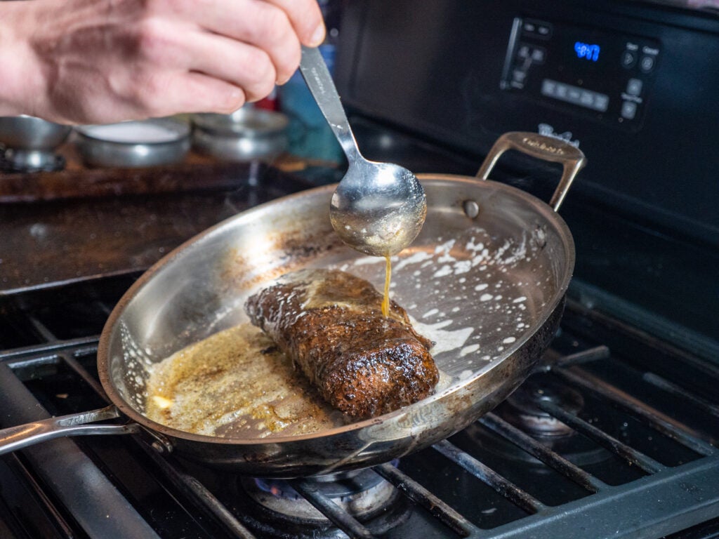 Pan searing a venison loin with butter.