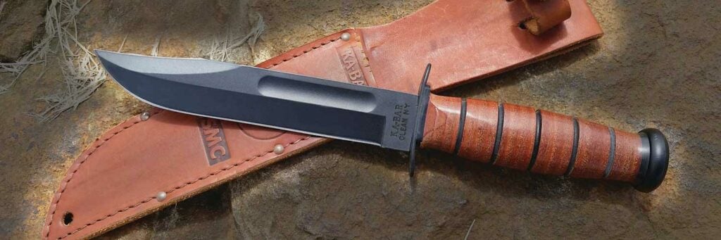 A knife and leather sheath on a rock ground.