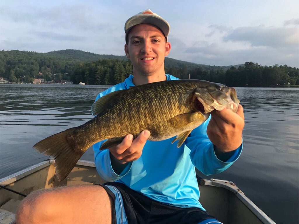 A young man holds up a smallmouth bass.
