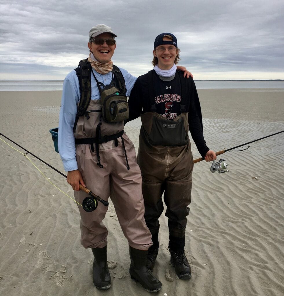 Two fishermen standing on the beach.