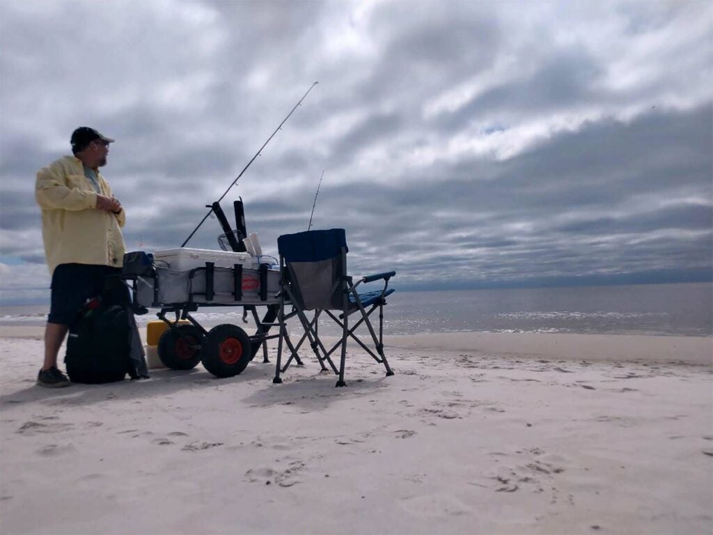 A man stands next to his fishing gear station.
