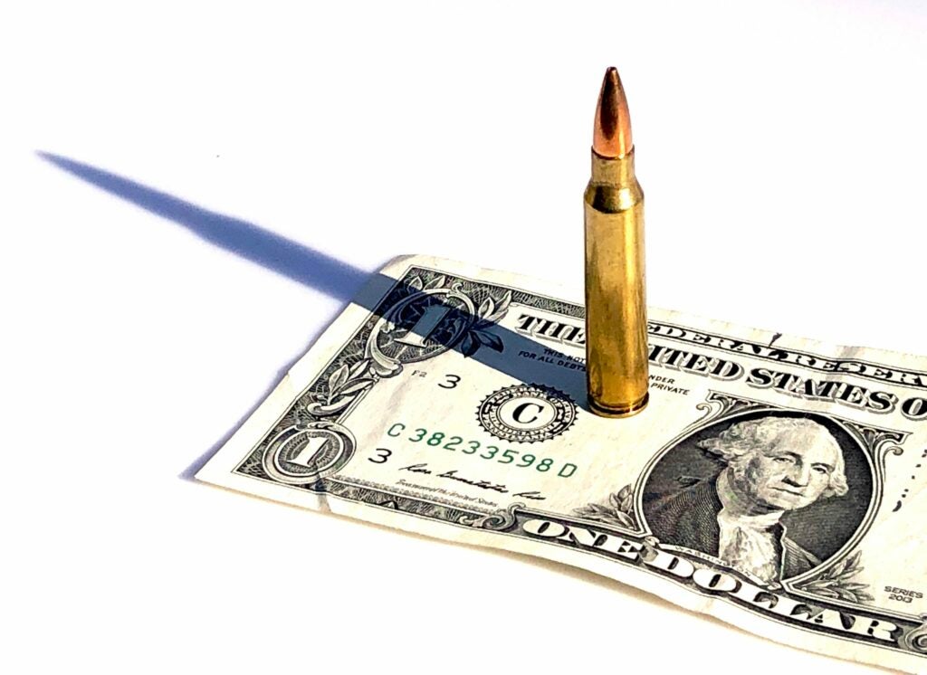 A .223 Remington cartridges standing on top of a dollar bill.