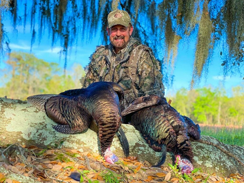 A hunter poses next to a turkey.